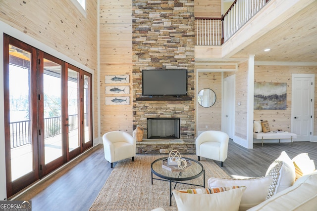 living area with wooden walls, a fireplace, wood finished floors, and french doors