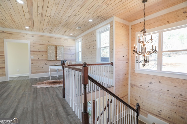 hallway featuring a healthy amount of sunlight, wood ceiling, dark wood finished floors, and an upstairs landing