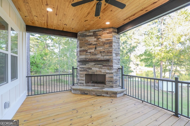 wooden deck featuring an outdoor stone fireplace and ceiling fan