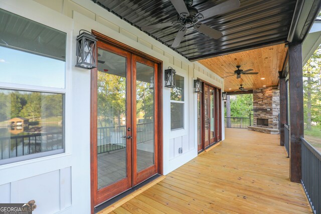 deck with a ceiling fan, french doors, and a stone fireplace