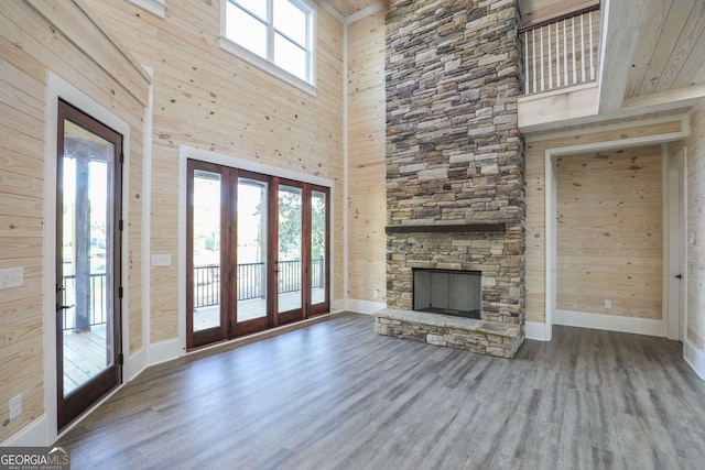 unfurnished living room featuring a wealth of natural light, hardwood / wood-style floors, and wooden walls