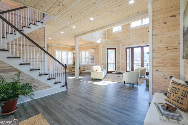 living area featuring wooden ceiling, wood walls, wood finished floors, a towering ceiling, and stairs