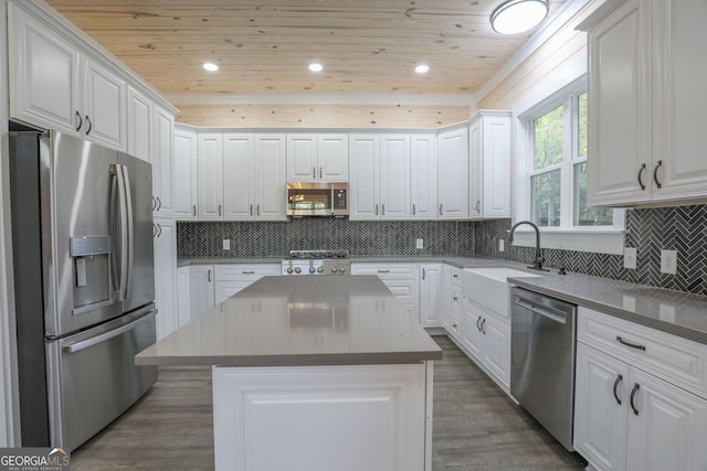 kitchen with appliances with stainless steel finishes, white cabinetry, a center island, and dark hardwood / wood-style floors