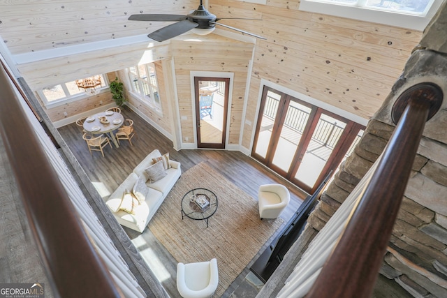 living area featuring wooden walls, vaulted ceiling, and wood finished floors