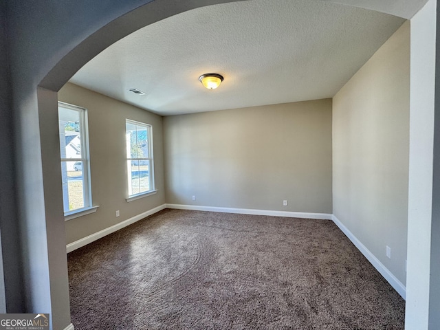 carpeted empty room with a textured ceiling