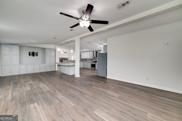 unfurnished living room featuring a textured ceiling, ceiling fan, hardwood / wood-style flooring, and lofted ceiling