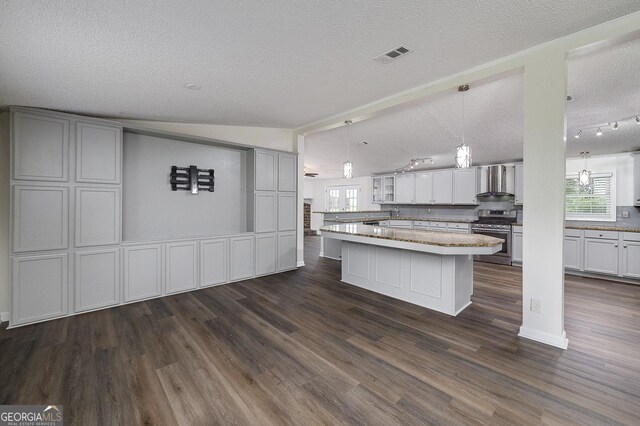 kitchen with dark hardwood / wood-style floors, a center island, stainless steel gas range, and wall chimney range hood