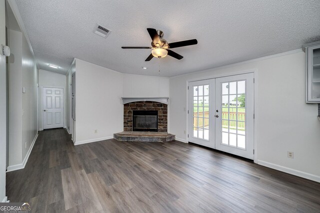 unfurnished living room with ceiling fan, dark hardwood / wood-style flooring, french doors, a fireplace, and a textured ceiling