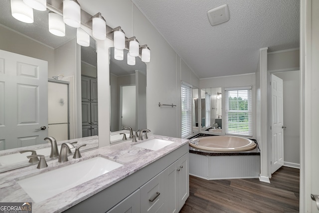 bathroom with ornamental molding, hardwood / wood-style flooring, double vanity, a textured ceiling, and plus walk in shower