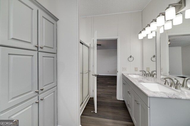 bathroom with wood-type flooring, dual bowl vanity, a textured ceiling, ceiling fan, and walk in shower