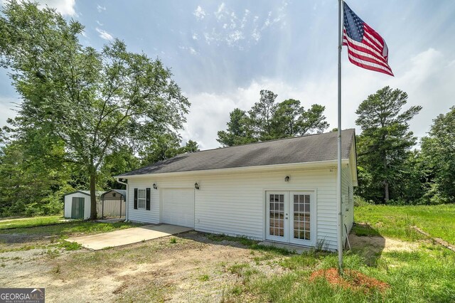 view of home's exterior featuring a garage, a shed, and french doors