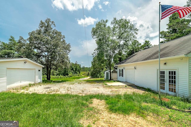 view of yard featuring french doors, an outdoor structure, and a garage