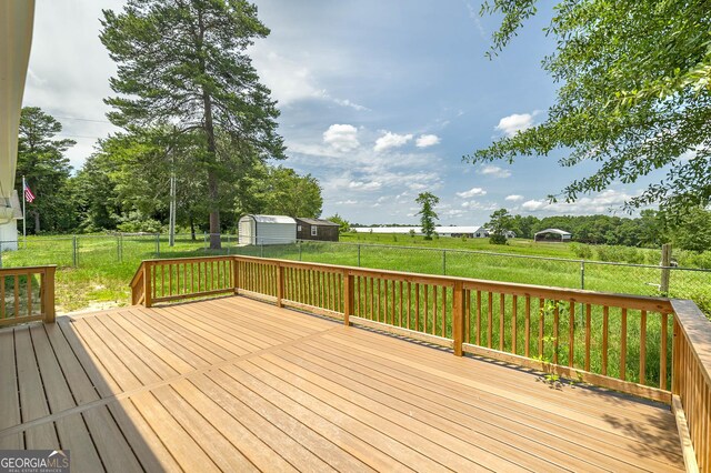 wooden terrace featuring a lawn and a storage unit