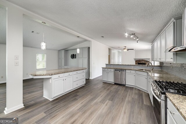 kitchen featuring appliances with stainless steel finishes, dark hardwood / wood-style floors, a kitchen bar, and a textured ceiling