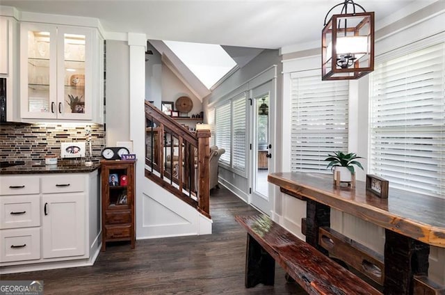 bar featuring stairway, dark wood-style flooring, decorative backsplash, vaulted ceiling, and hanging light fixtures