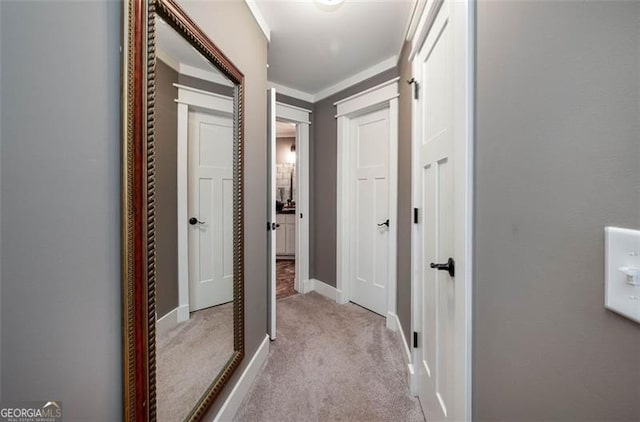 corridor with crown molding and light carpet