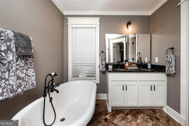 bathroom with baseboards, a freestanding bath, ornamental molding, and vanity