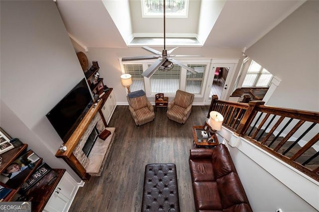 living room with ceiling fan, a raised ceiling, and dark hardwood / wood-style flooring