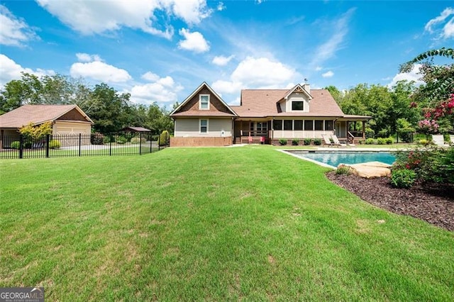 rear view of property featuring a garage, fence, a yard, a sunroom, and a fenced in pool