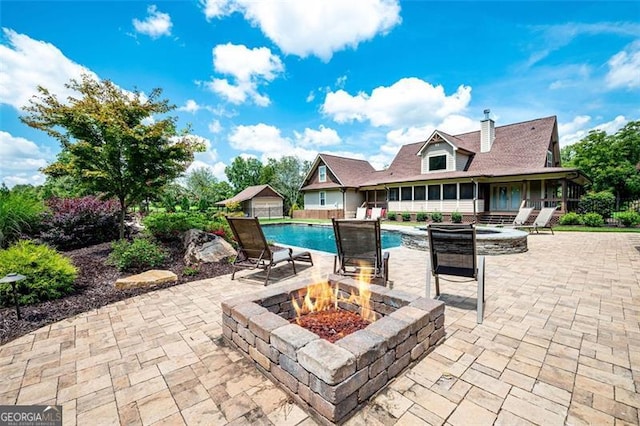 view of patio with an outdoor pool, an outdoor fire pit, and a sunroom