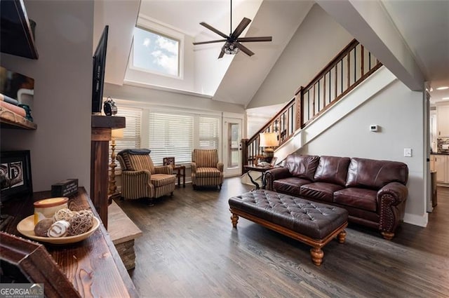 living area featuring stairs, a fireplace, a high ceiling, wood finished floors, and a ceiling fan