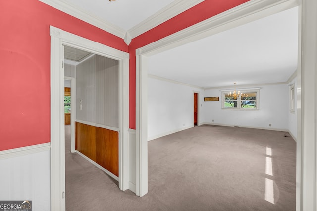 empty room with plenty of natural light, ornamental molding, light carpet, and a chandelier