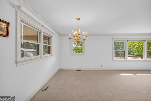 carpeted spare room with ornamental molding, a wealth of natural light, and a notable chandelier