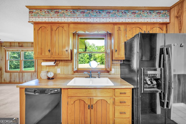 kitchen with wood walls, black appliances, sink, carpet flooring, and a textured ceiling