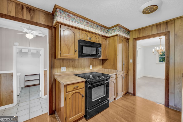 kitchen with light wood-type flooring, ornamental molding, a textured ceiling, ceiling fan with notable chandelier, and black appliances