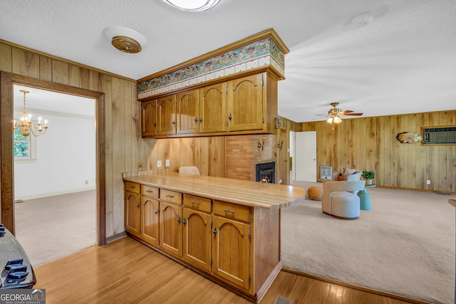 kitchen featuring kitchen peninsula, pendant lighting, light hardwood / wood-style floors, and wooden walls