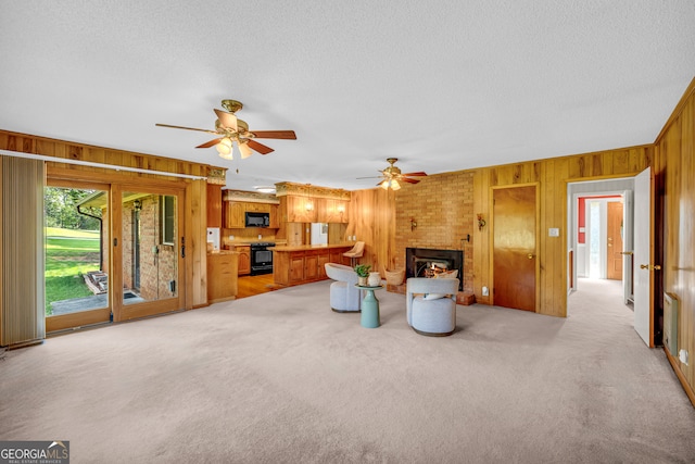 living room with wooden walls, a fireplace, ceiling fan, and light colored carpet