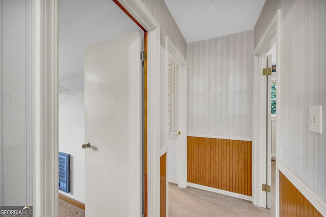 hall with light colored carpet and wooden walls