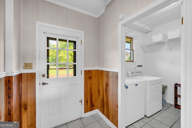 laundry room featuring wooden walls, washer and clothes dryer, light tile patterned floors, and ornamental molding