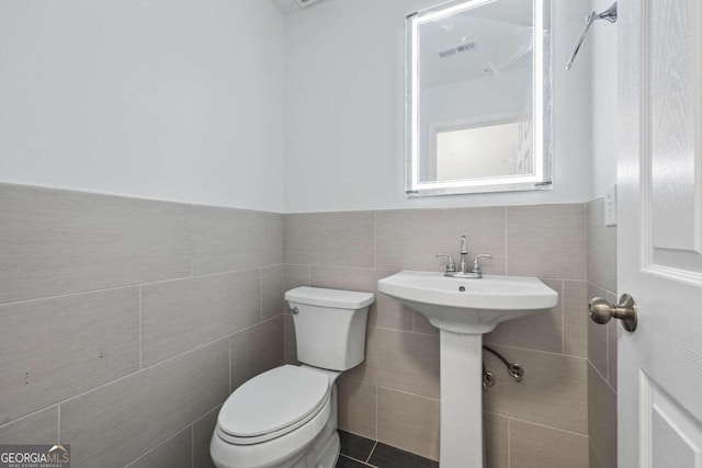 bathroom featuring tasteful backsplash, toilet, tile patterned floors, and tile walls