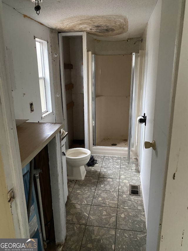 bathroom featuring tile patterned floors, a textured ceiling, walk in shower, and toilet