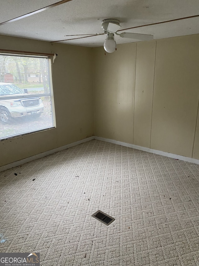 carpeted empty room featuring a textured ceiling and ceiling fan