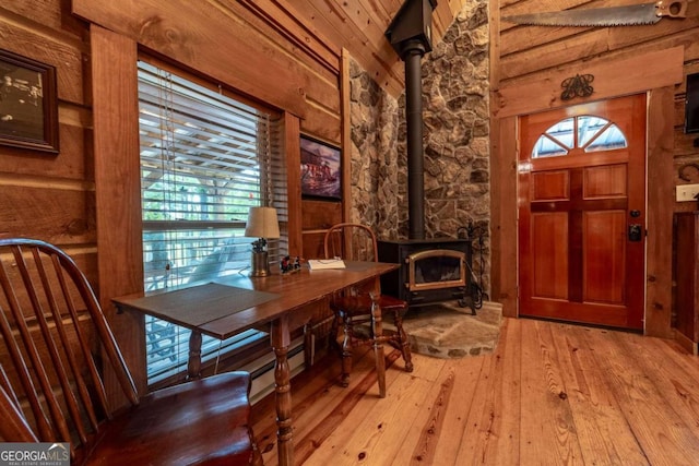 foyer entrance with light wood-type flooring and a wood stove