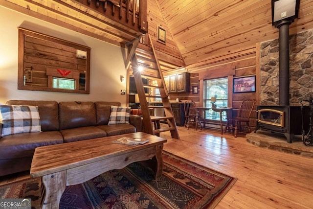 living room featuring high vaulted ceiling, wood-type flooring, a wood stove, wooden ceiling, and wooden walls