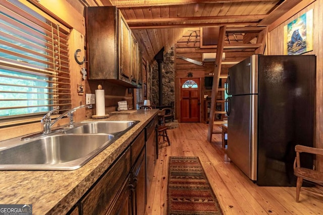 kitchen featuring wood walls, light hardwood / wood-style flooring, sink, black fridge, and wood ceiling