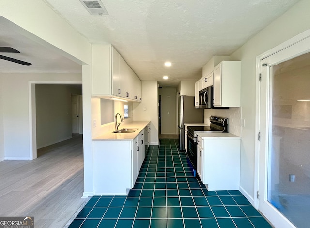 kitchen with light countertops, visible vents, appliances with stainless steel finishes, white cabinetry, and a sink