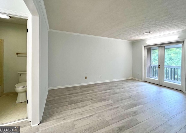 unfurnished room with a textured ceiling, light wood-style flooring, visible vents, baseboards, and ornamental molding