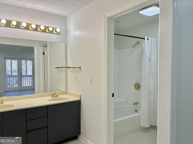 full bathroom with double vanity, shower / bath combo, a textured ceiling, and a sink