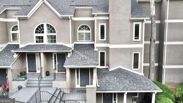 view of front facade with roof with shingles and stucco siding