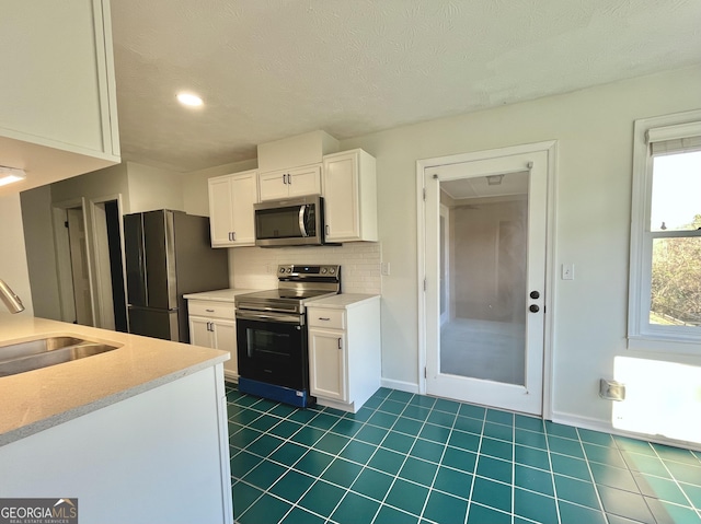 kitchen featuring stainless steel appliances, light countertops, white cabinetry, and a sink