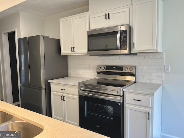 kitchen featuring white cabinetry, stainless steel appliances, and backsplash