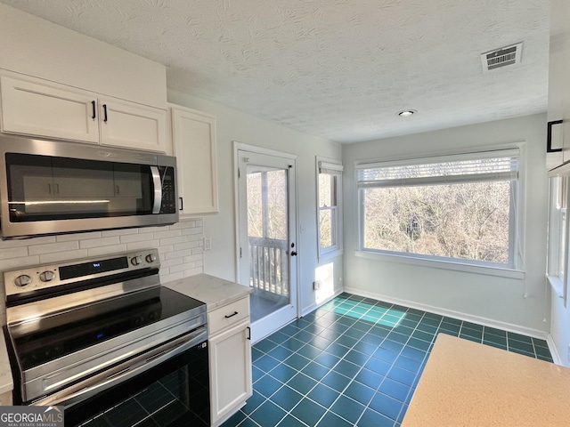 kitchen featuring stainless steel appliances, visible vents, white cabinets, light countertops, and tasteful backsplash