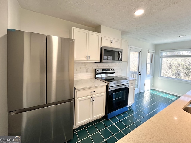 kitchen featuring stainless steel appliances, decorative backsplash, light stone countertops, and white cabinets