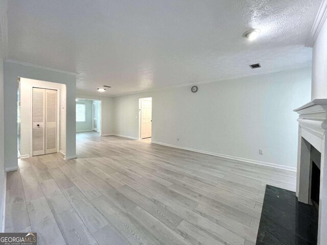 unfurnished living room with a textured ceiling, light hardwood / wood-style floors, and crown molding