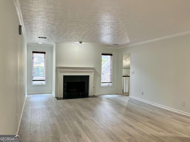 unfurnished living room featuring ornamental molding, light wood finished floors, plenty of natural light, and a fireplace with flush hearth