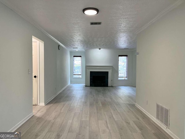 unfurnished living room with a healthy amount of sunlight, light wood finished floors, and visible vents